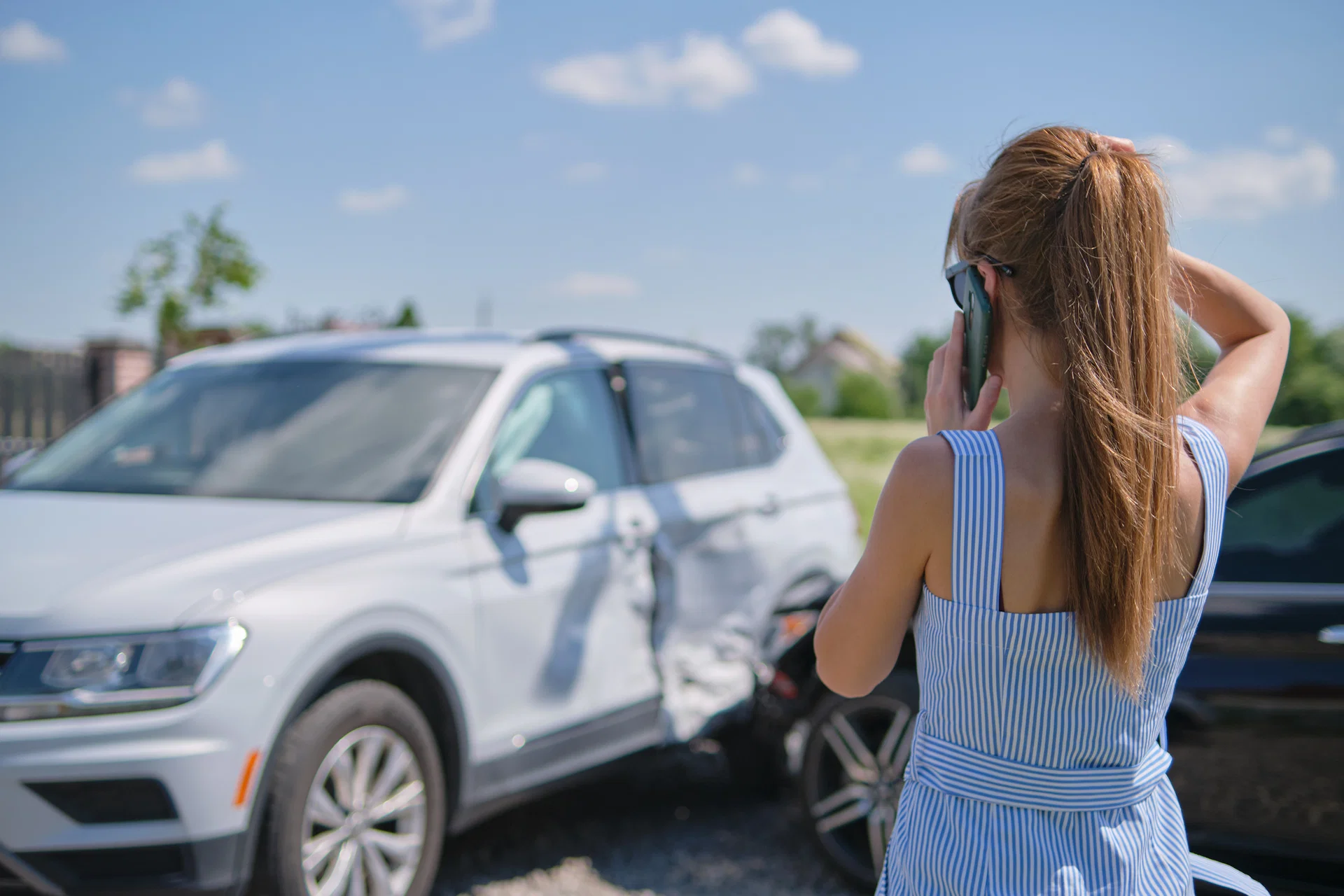 Montana driver standing next to a damaged car with mountains in the background